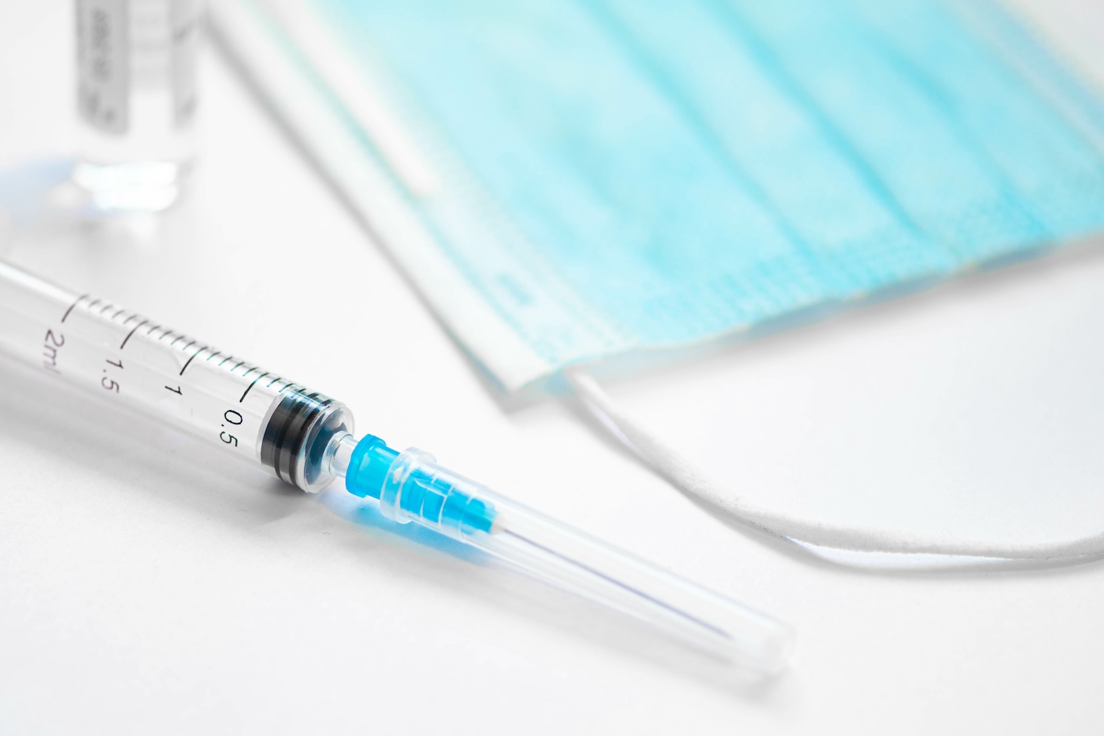 Image of a vaccine vial and a mask. Adobe Stock image.