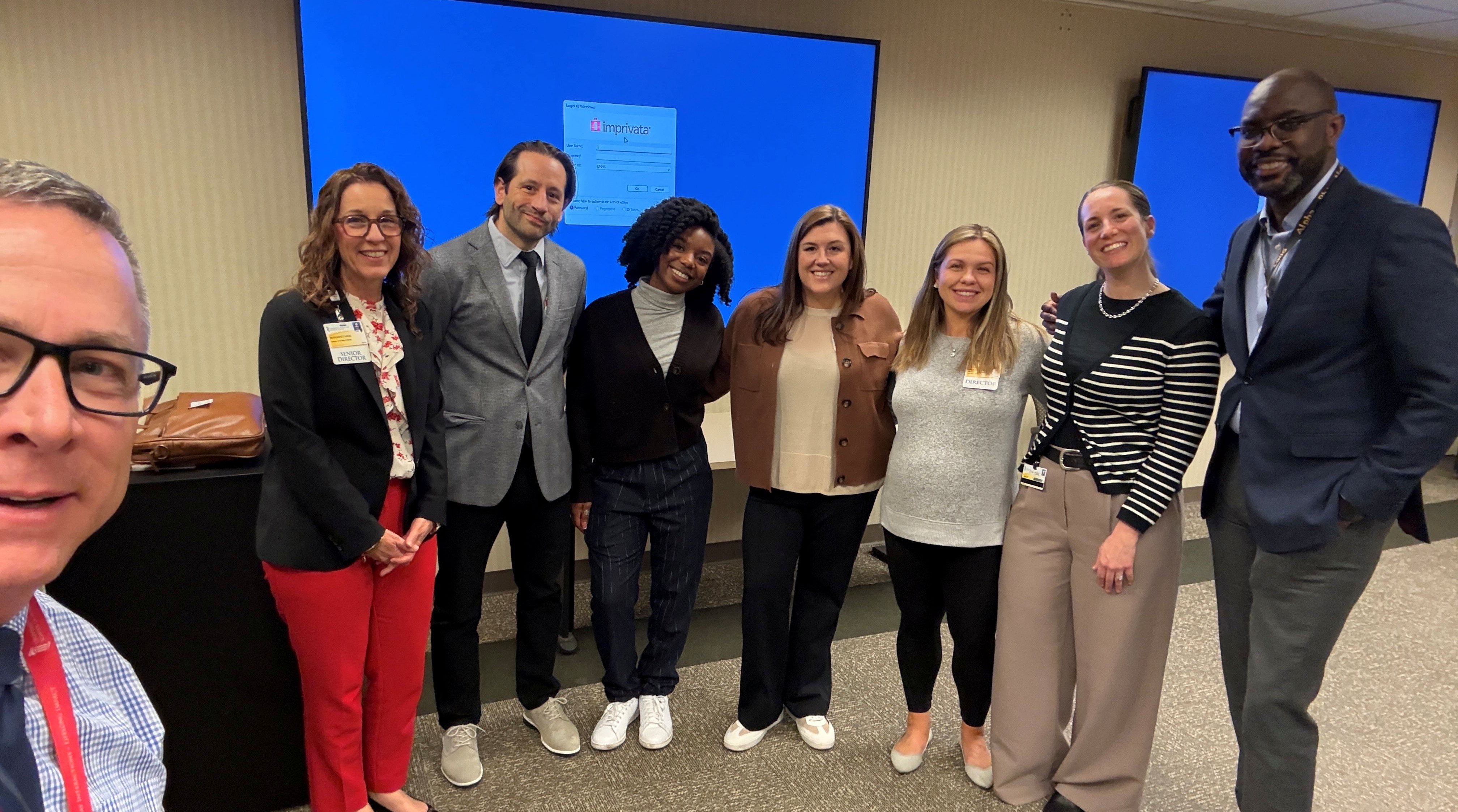 UMD OCC Members smiling with UMMC Staff in front of a blue screen 