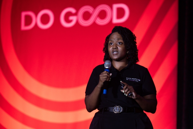 T-Kea Blackman with microphone and the words "Do Good" in the background